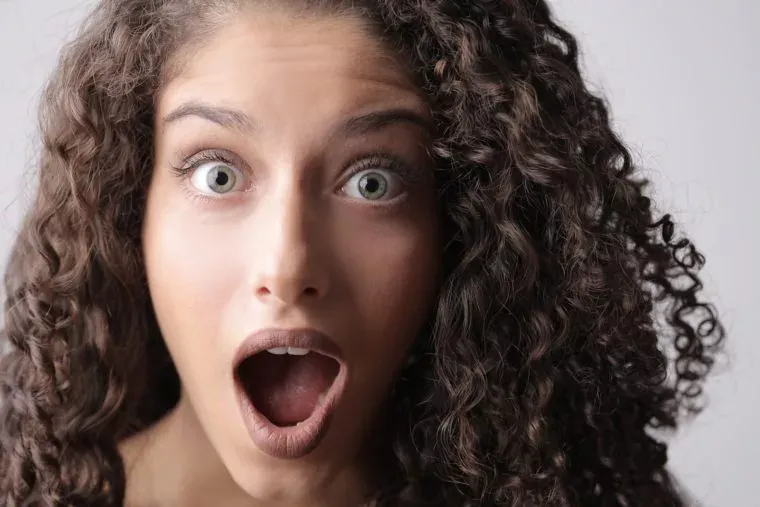 Close-up Photo of Shocked Woman With Brown Curly Hair