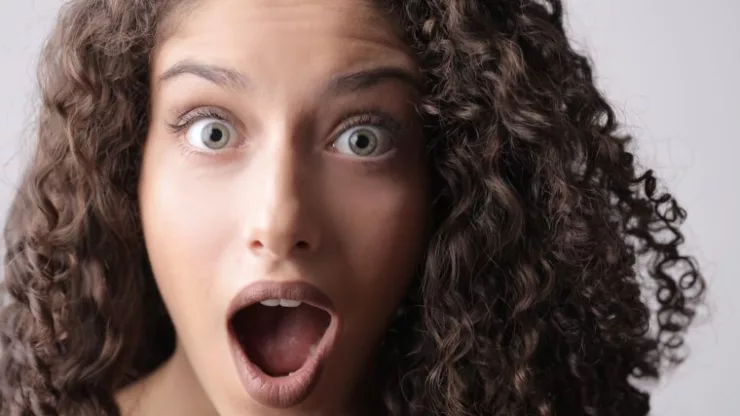 Close-Up Photo Of Shocked Woman With Brown Curly Hair