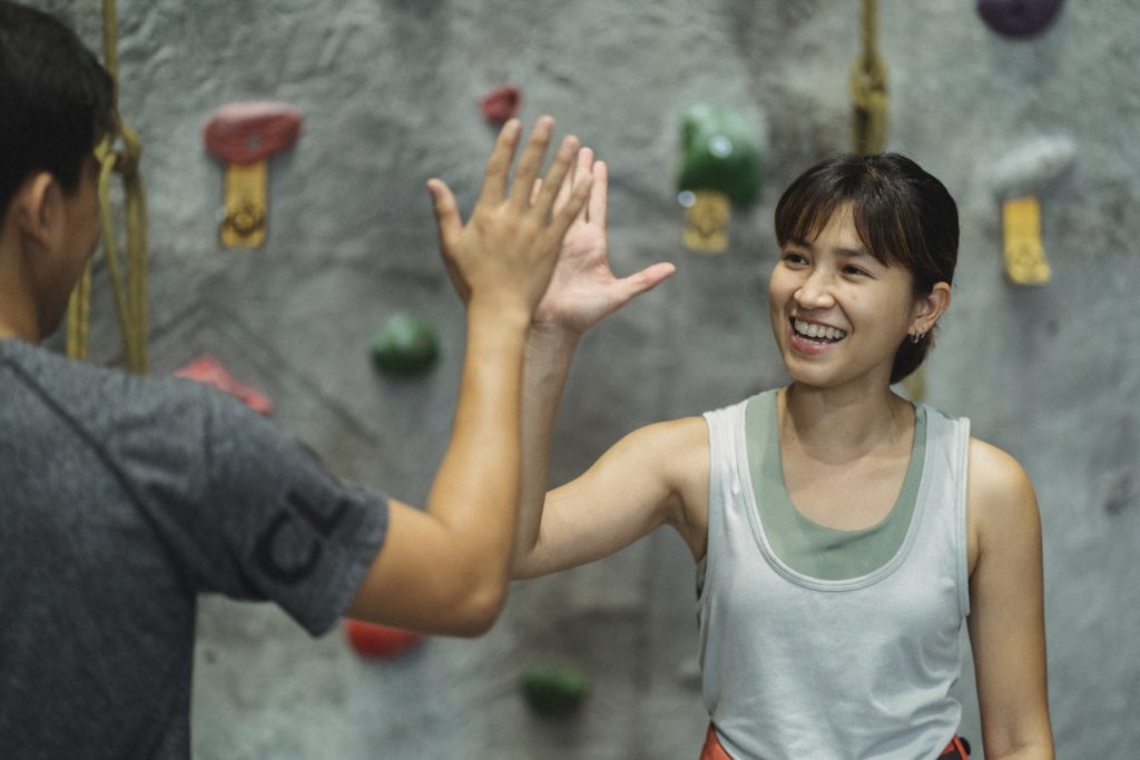 Happy Asian Climber And Unrecognizable Trainer Giving High Five